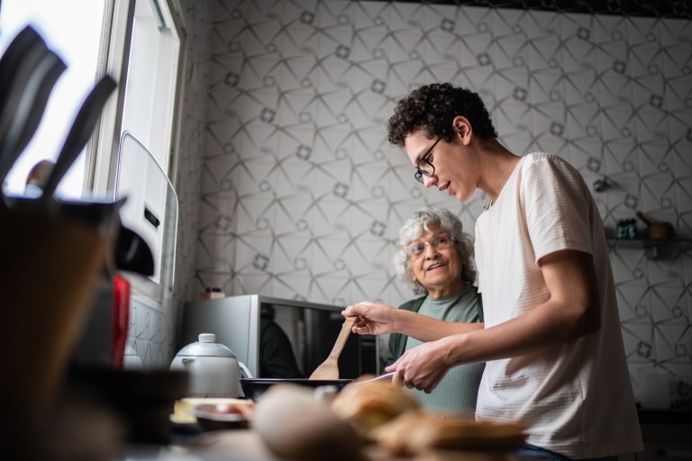 Junger Mann und alte Frau beim gemeinsamen Kochen.