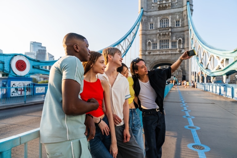 Gruppe Jugendlicher auf der Tower Bridge in London, die ein Selfie machen.